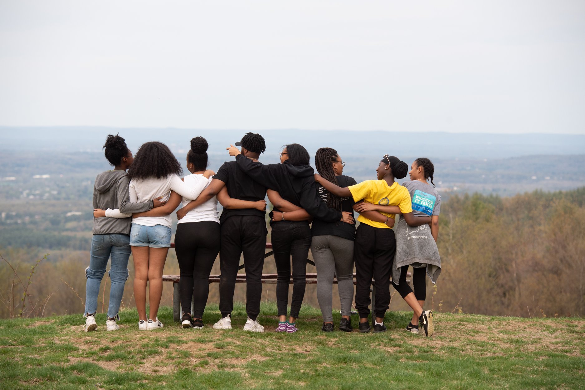 a group of 8 young people on a hill with their arms around each other