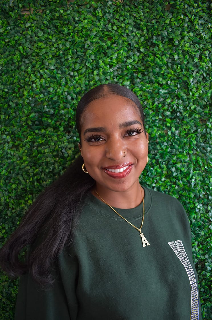 Aisha with a big smile and a pendant necklace with an 'A' on it.